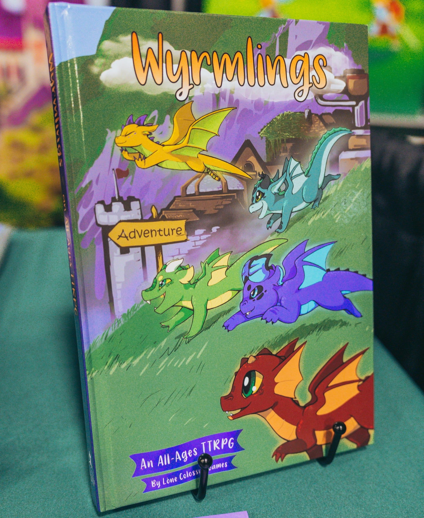 Photo of the Wyrmlings RPG hardcover showing five young wyrmlings setting out on adventure