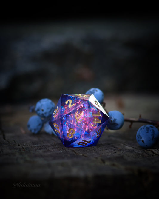 photo of the mysteries of magic sharp-edged resin d20 with blue and pink resin and foil insert